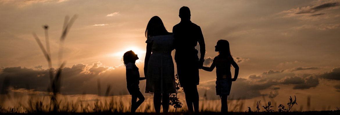 a-family-standing-in-a-field-at-sunset.jpg a family standing in a field at sunset